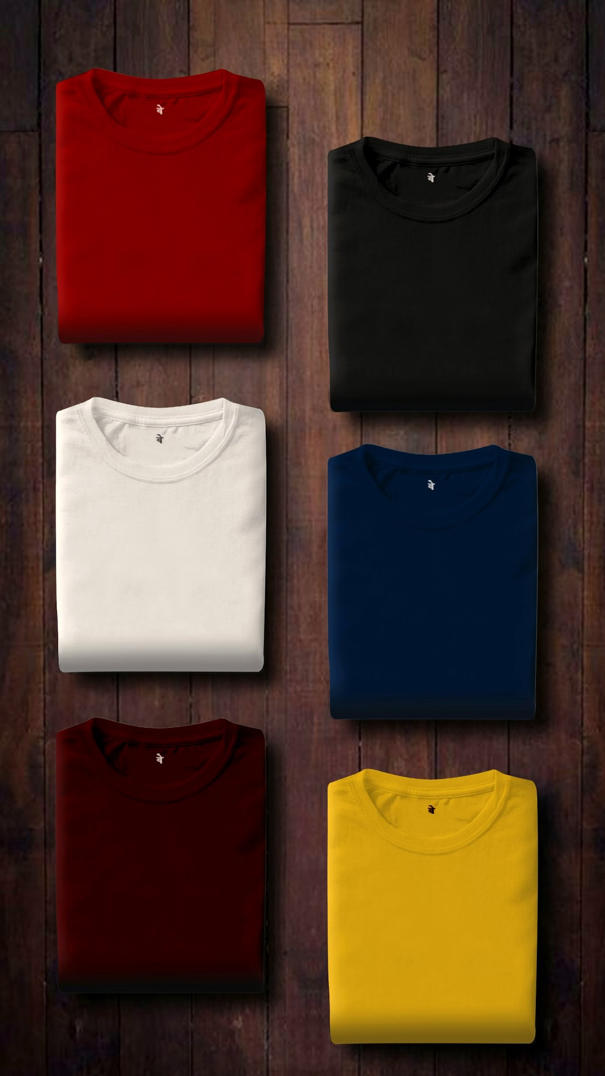Folded cotton t-shirts in red, black, white, navy, burgundy and yellow on dark wood