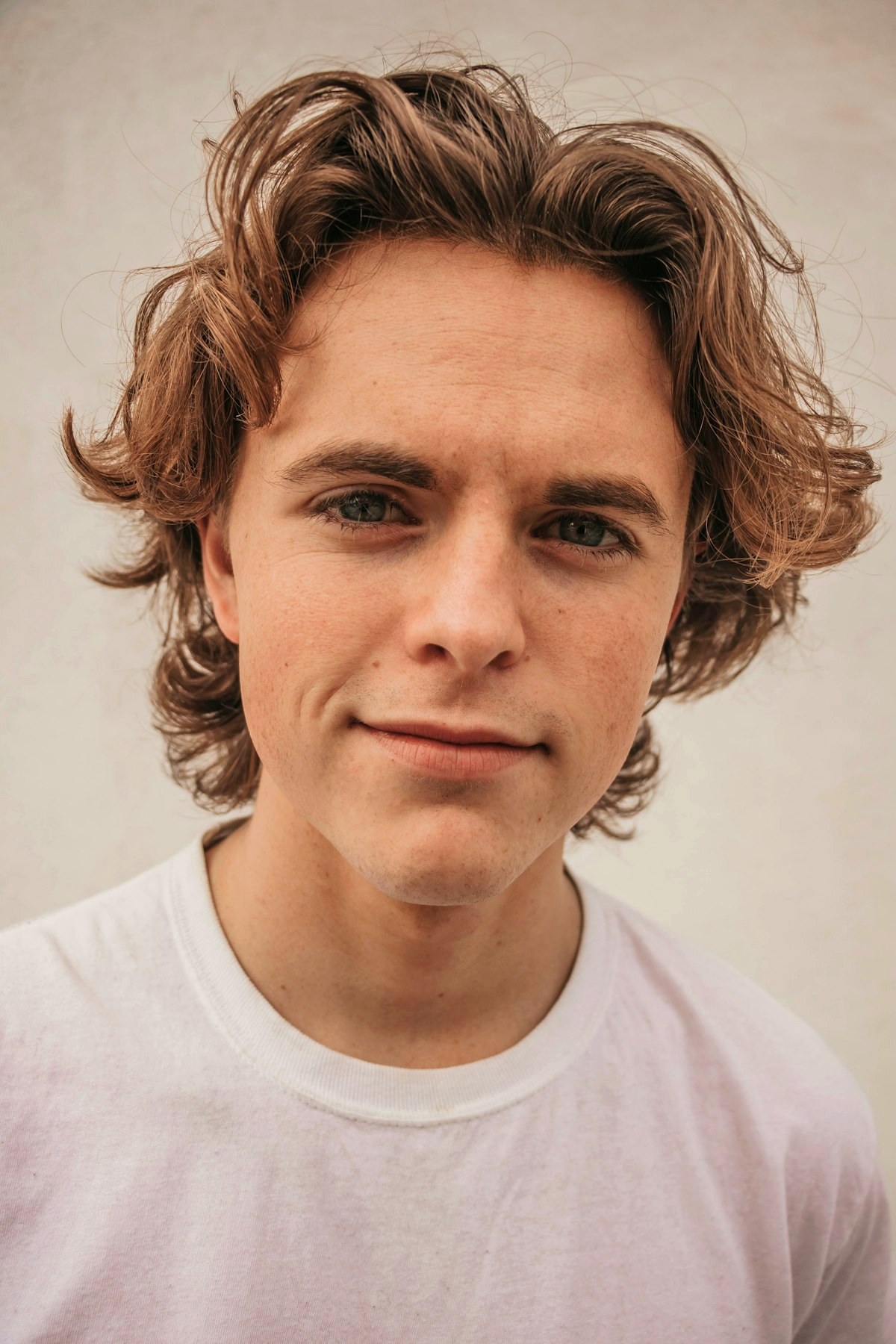 Young man with wavy hair wearing a plain white t-shirt